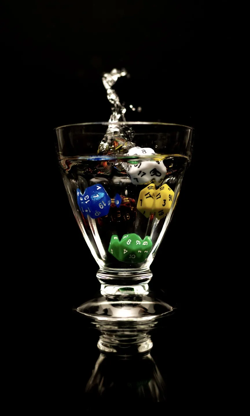 Coloured dice frozen mid-splash in a glass of water